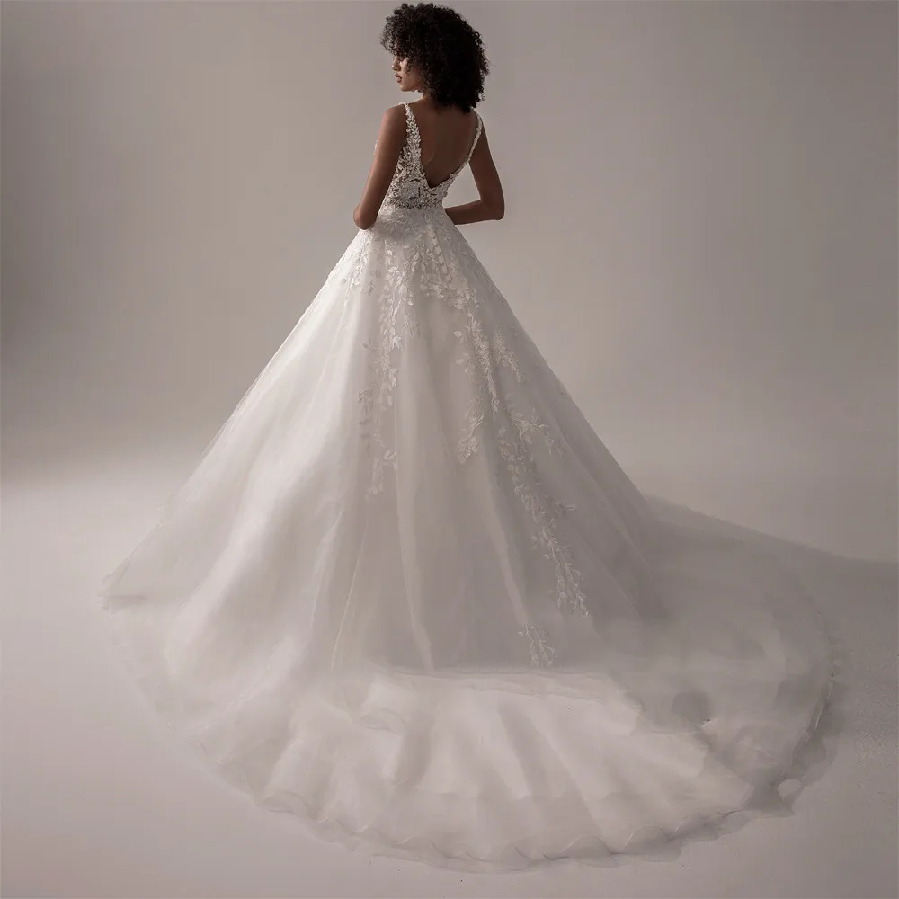 Back view of a boho-style ivory wedding dress featuring a low V-back, lace appliques, and a sweeping train.