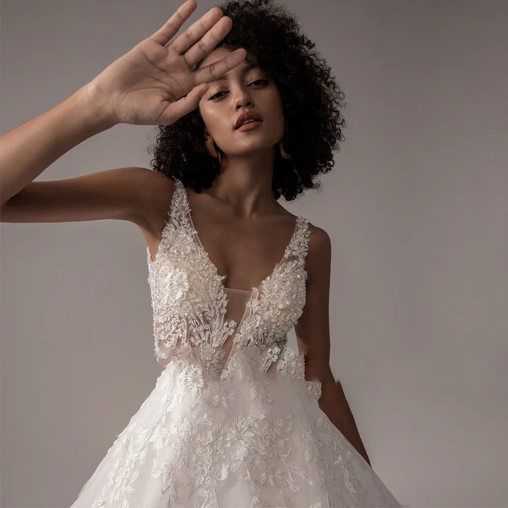 Close-up portrait of a bride wearing a sleeveless lace wedding dress with a deep V-neck and floral applique detail.
