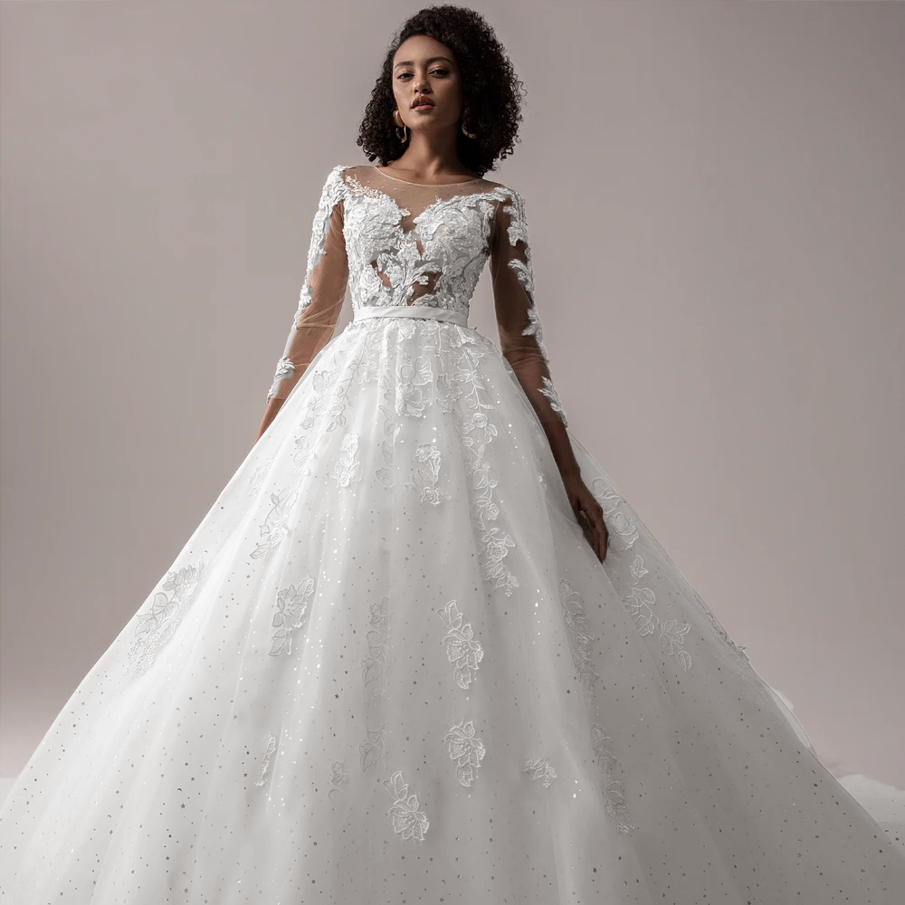 Front view of a long-sleeve, ivory A-line wedding dress featuring intricate lace appliques and a flattering waistline.