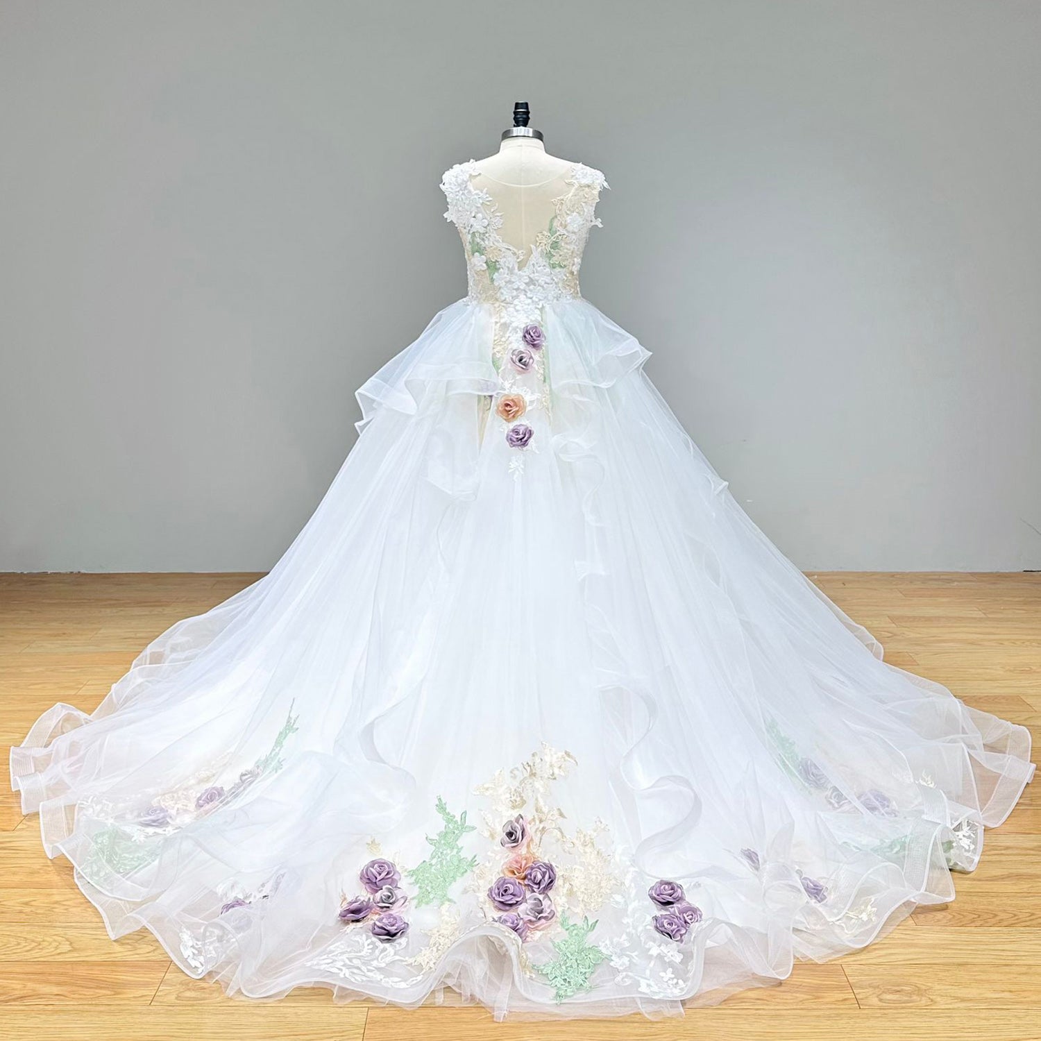 Dramatic full back view of an elegant ball gown wedding dress on a mannequin, showcasing the luxurious illusion back with intricate lace appliques and a sweeping train.