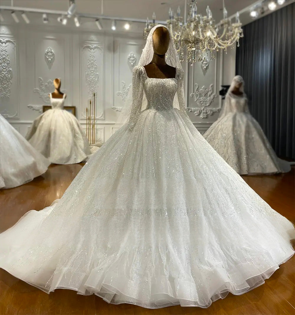 Front view of a vintage long sleeve bridal ball gown displayed on a mannequin, showcasing the shimmering, fully-beaded bodice, square neckline, and voluminous sparkly skirt.