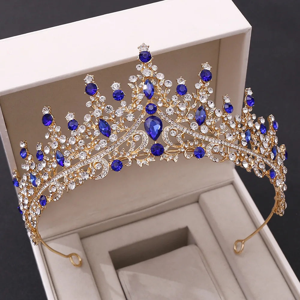 A royal bridal tiara in gold-tone metal, featuring deep blue teardrop crystals and clear rhinestone embellishments.