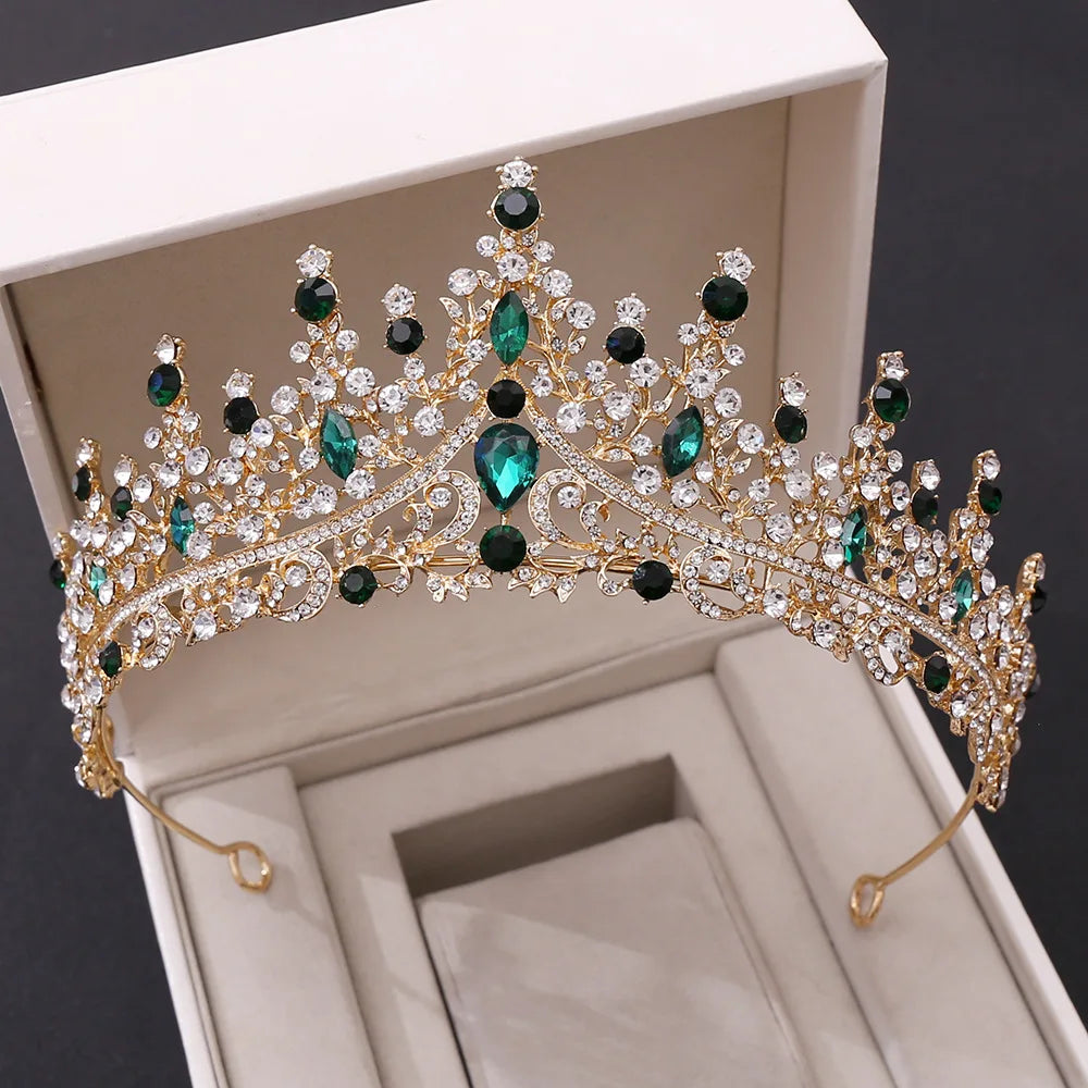 A vintage-style wedding crown featuring striking emerald green crystals set in a decorative gold-tone frame.