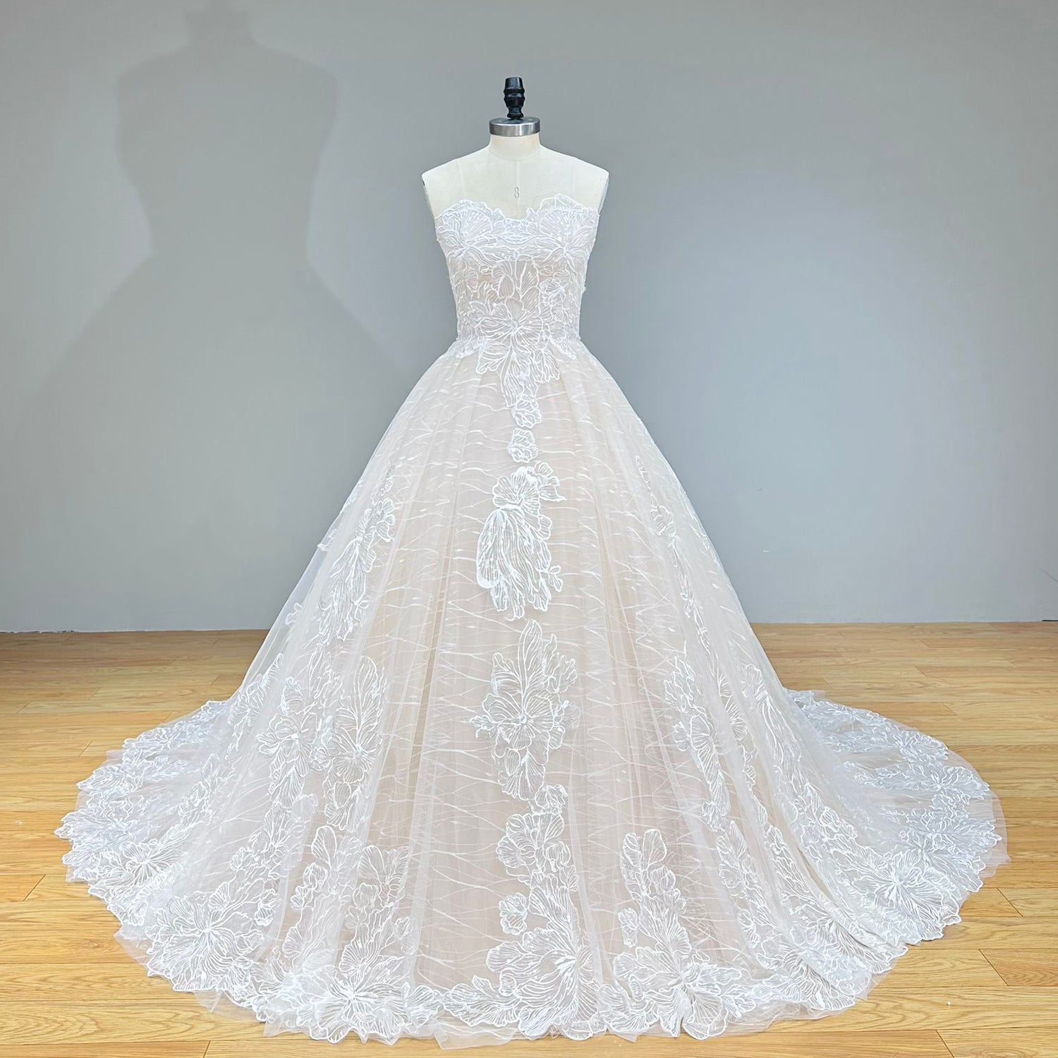 Front view of a vintage-style strapless ball gown wedding dress showing a structured lace bodice and a sweeping glitter tulle skirt on a dress form.