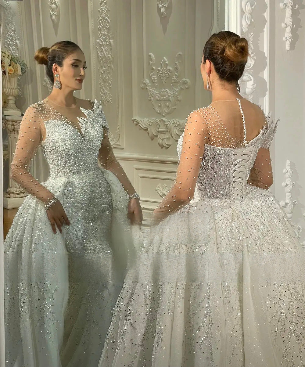Close-up detail of a luxury bridal bodice showing intricate hand-sewn pearl beading, crystal embellishments, and a structured sweetheart neckline.
