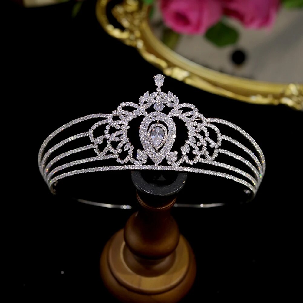Front view of the luxury cubic zirconia wedding headband diadem crown showcased upright on a smooth wooden pedestal stand against a black backdrop.