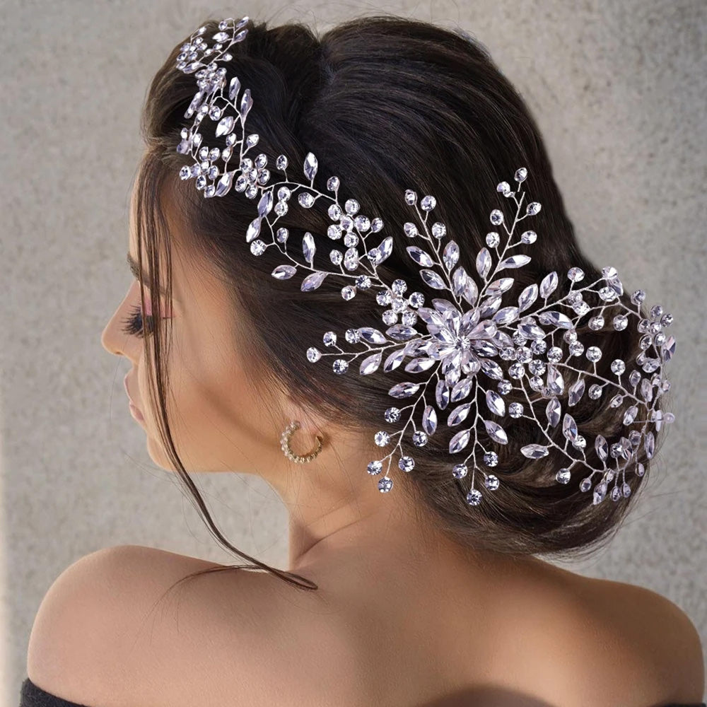 Rear profile view of a bride with a braided updo wearing an oversized, flexible silver rhinestone wedding headpiece with branching leaf sprays.