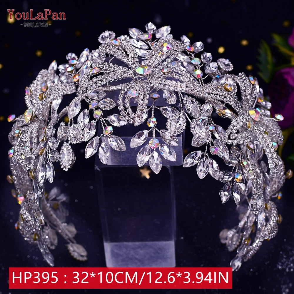 High-angle shot of a premium silver-plated royal bridal tiara crown, heavily embellished with iridescent rhinestones on a clear display stand.