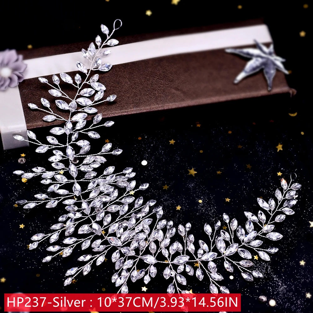 High-angle display of a long, handmade silver crystal wedding hair accessory laid out near a brown gift presentation box with a matching ribbon flowe