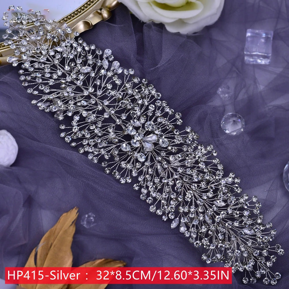 Full flat lay view of a wide rhinestone bridal hair piece with dense, sprawling crystal branches arranged over a soft purple tulle background.