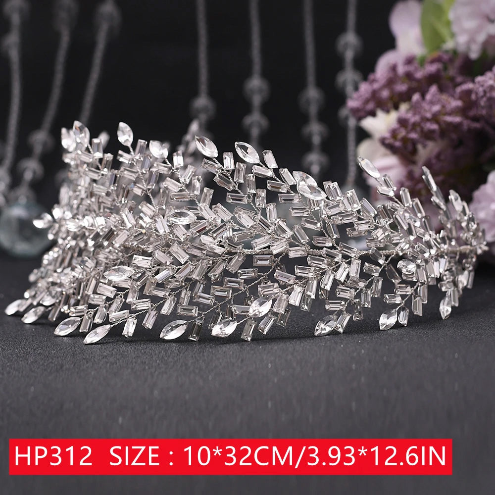 Front display of an intricate silver rhinestone bridal tiara featuring a dense web of faceted rectangular baguette and marquise cut crystals over a dark base