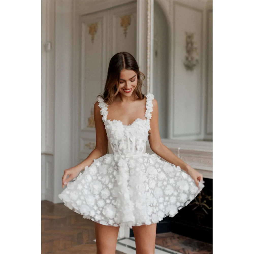 A model wearing a white, strapless, knee-length prom dress with a corseted bodice, sparkling sequins, and 3D floral lace embroidery.