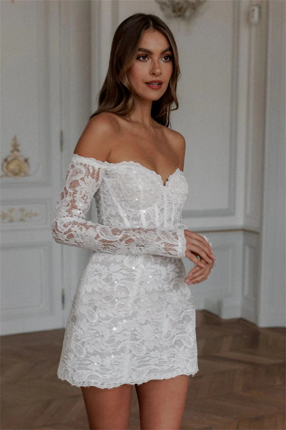 Romantic short lace bridal gown with an off-shoulder design, long sleeves, and delicate scalloped hem, ideal for civil ceremonies or reception wear.