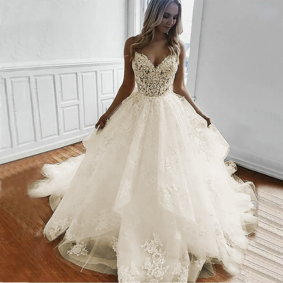 A bride wearing a voluminous white tulle A-line wedding dress with lace appliqué accents and elegant spaghetti straps.