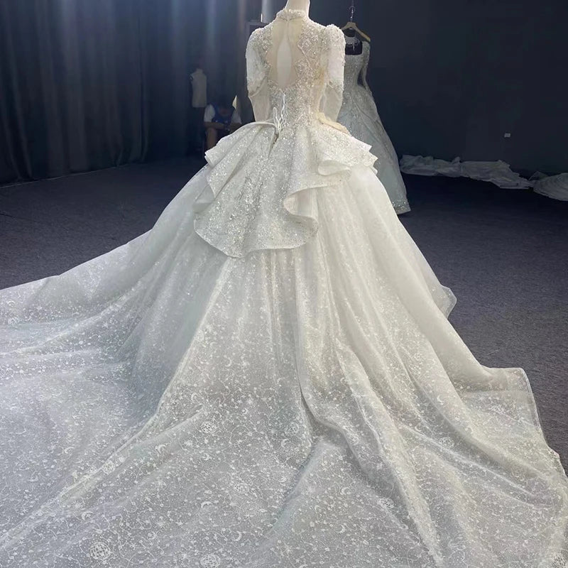 Wide angle rear view of a luxury organza wedding ball gown featuring a grand, sparkling cathedral-length train and a lace-up back.