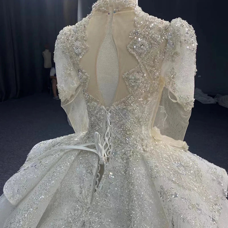 Complete frontal view of a women's luxury novelty organza wedding dress with full beaded sleeves, a square neck, and a voluminous ball gown silhouette.
