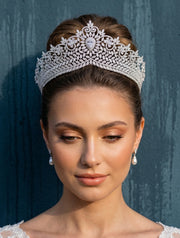 A bride with an elegant hair updo wearing a high-end zirconia wedding bridal crown tiara and matching pearl drop earrings.