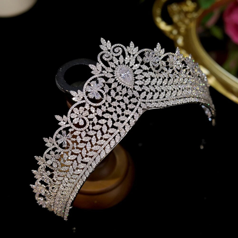 Side angle display of a stunning cubic zirconia royal wedding tiara crown placed on a wooden display stand.