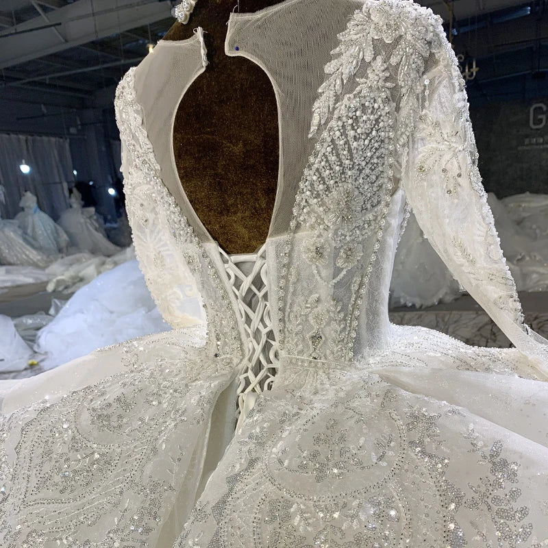 Close-up view of the sheer long sleeves, showcasing the exquisite hand-beaded pearl detailing and trailing floral lace patterns along the arms.
