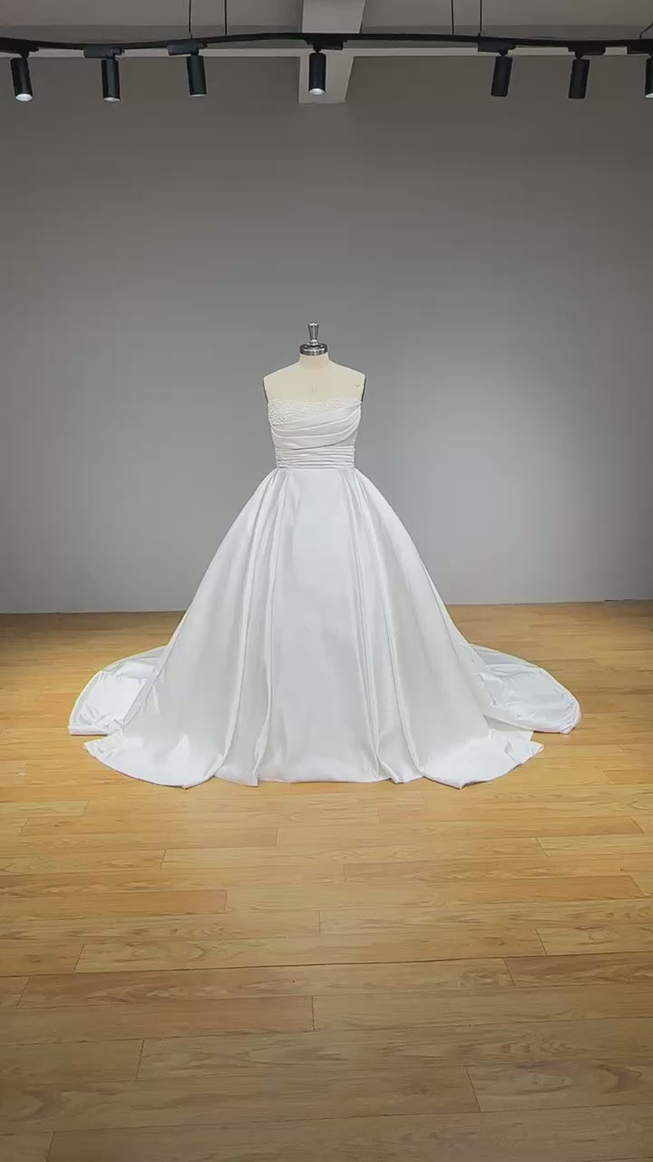 Load video: Light Effect Satin Off-Shoulder Ball Gown Wedding Dress with Pearls and Pleated Bodice