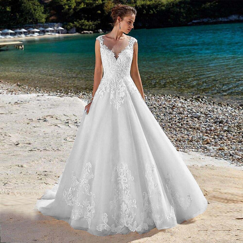 A wide-angle view of a bride wearing an elegant sleeveless A-line wedding dress, walking along the beach shore.