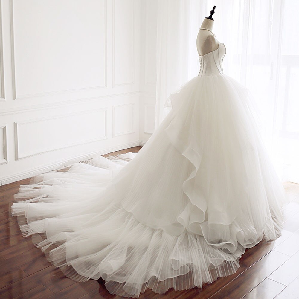 Rear view of an A-line wedding gown on a mannequin, showcasing the corset back and layered tulle skirt train.
