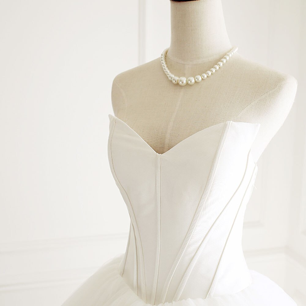 Close-up detail of the corset bodice and pearl necklace on an A-line wedding gown.