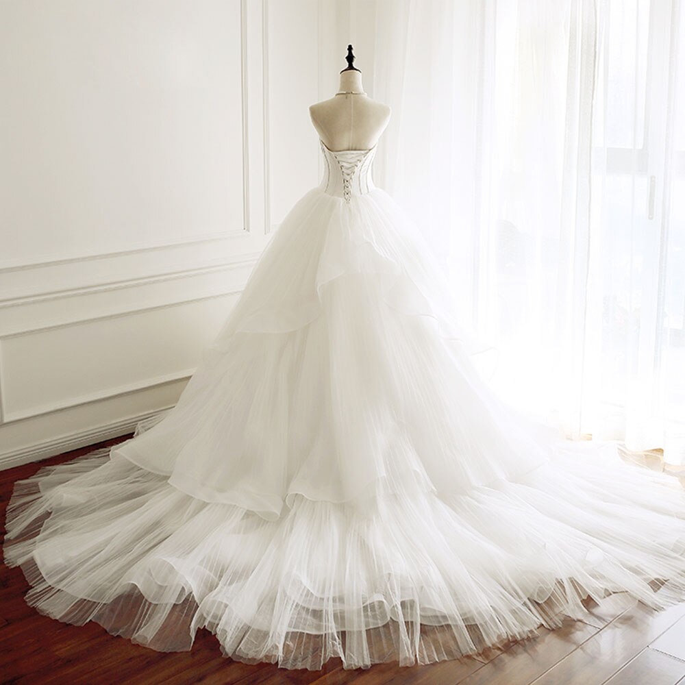 Elegant back view of an A-line bridal dress on a mannequin featuring a corset lace-up back and dramatic tulle train.