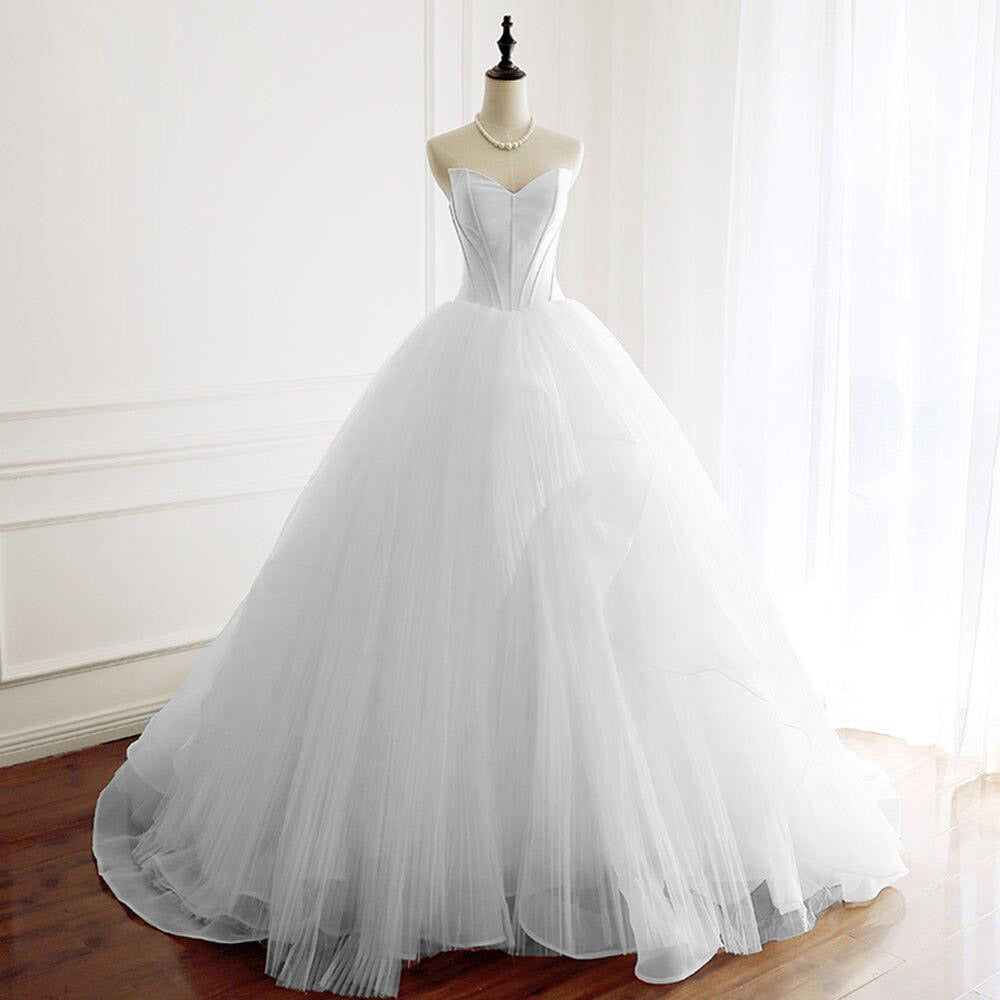 Mannequin display of a white A-line wedding dress featuring a minimalist corset bodice and voluminous skirt.