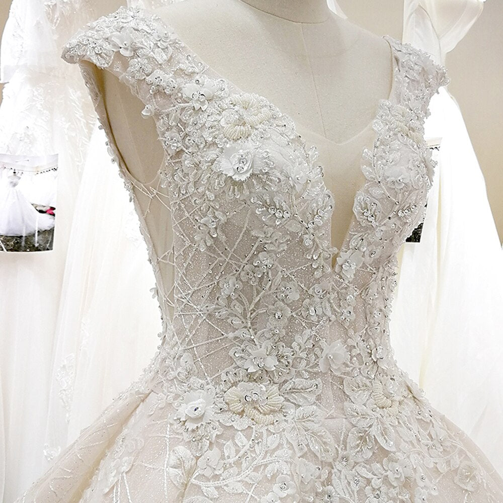 Close-up of the bodice on a V-neck ball gown wedding dress, highlighting intricate three-dimensional lace flowers.