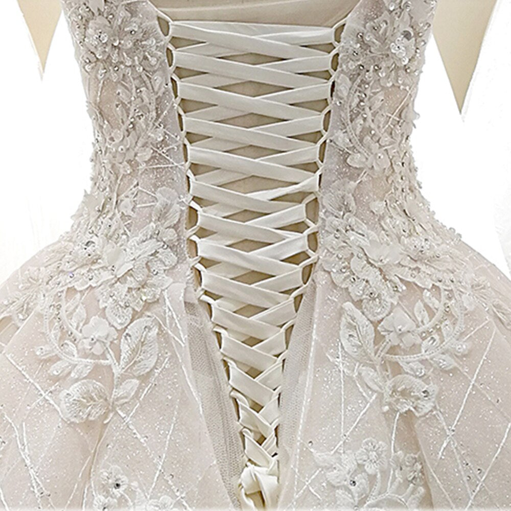 Back view of a princess-style wedding dress on a mannequin, showcasing a corset lace-up back design.