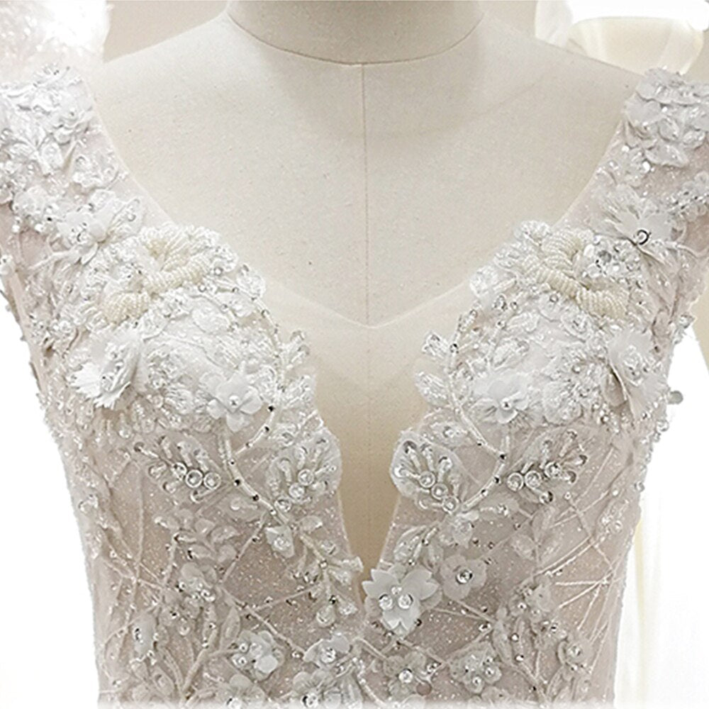 Detailed close-up of the delicate lace floral appliques and beadwork on the bodice of a princess wedding dress.