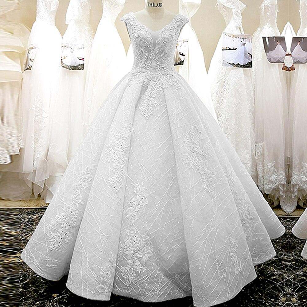 A princess-style wedding dress on a mannequin featuring a V-neckline, cap sleeves, and intricate lace flower appliques.