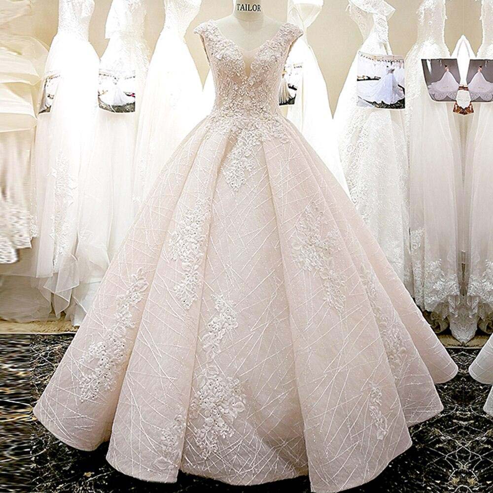 An elegant ball gown wedding dress with a V-neck, cap sleeves, and detailed lace appliques on a voluminous skirt.