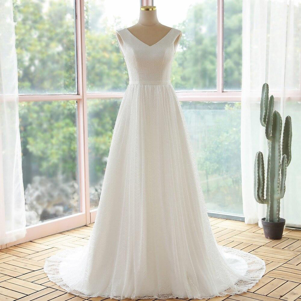 Elegant A-line lace bridal gown with a V-neckline and flowing train, displayed on a dress form.