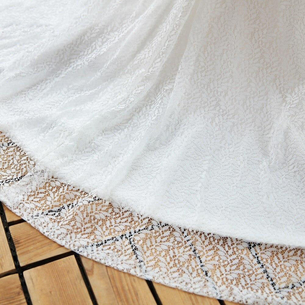 Close-up view of the intricate lace fabric detail on the hem of a flowing wedding dress train.