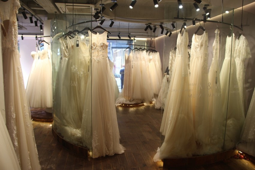 A professional boutique interior view showcasing a curated collection of bridal wedding gowns hanging along a curved display rack.