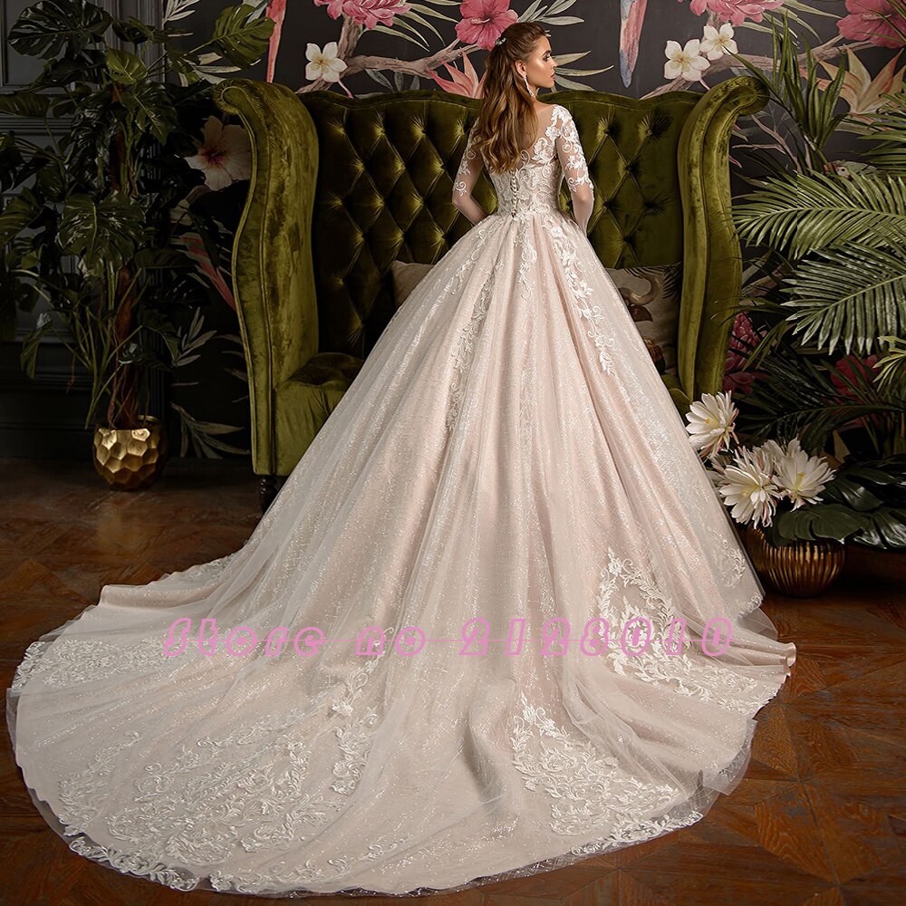 Rear view of the shiny ball gown wedding dress showcasing the long lace sleeves, intricate lace appliques, and a sweeping chapel train.