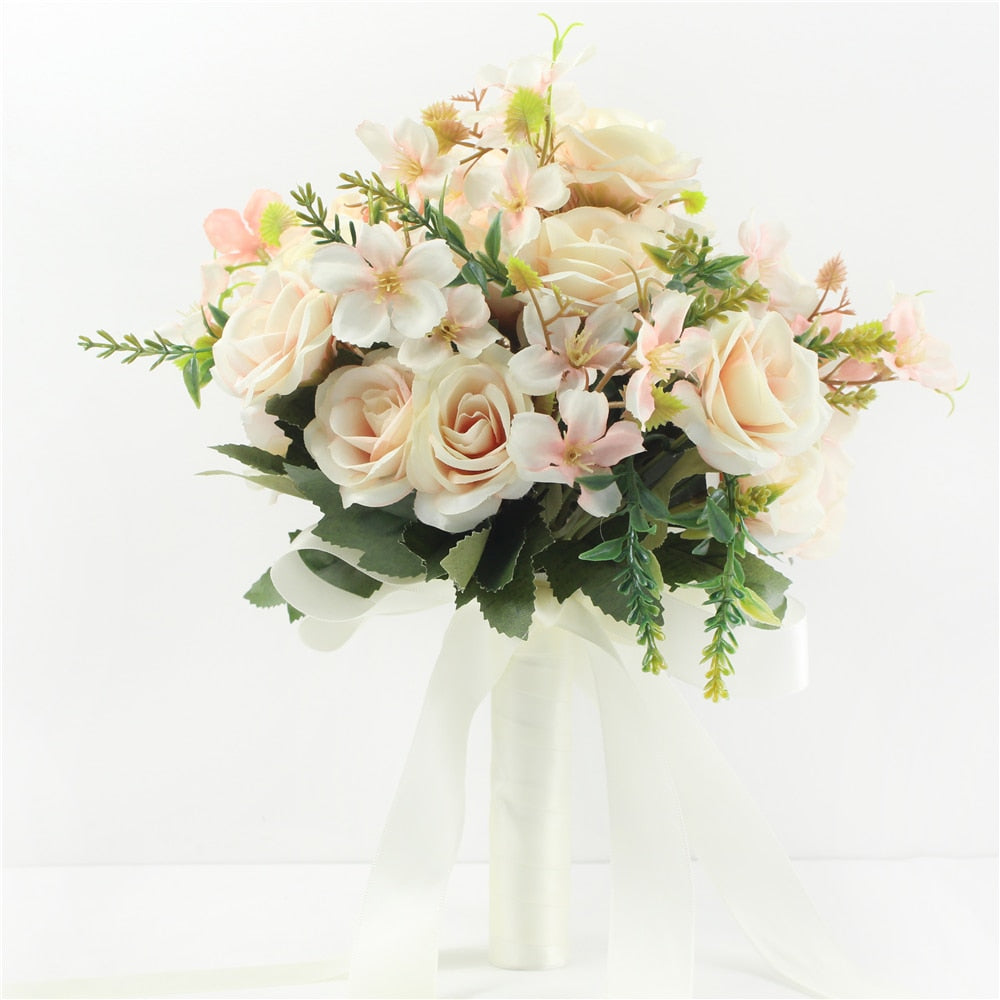 Elegant studio product shot of a minimalist cream-colored faux wedding bouquet featuring silk peach roses, matching filler flowers, and long ivory satin ribbons.