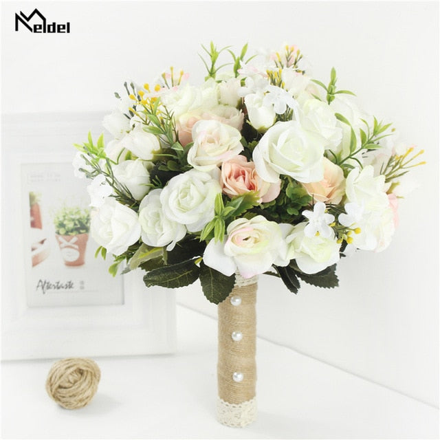 Front look at a round artificial flower wedding bouquet filled with creamy white and blush pink silk roses, built with a decorative burlap and lace handle next to a white photo frame.