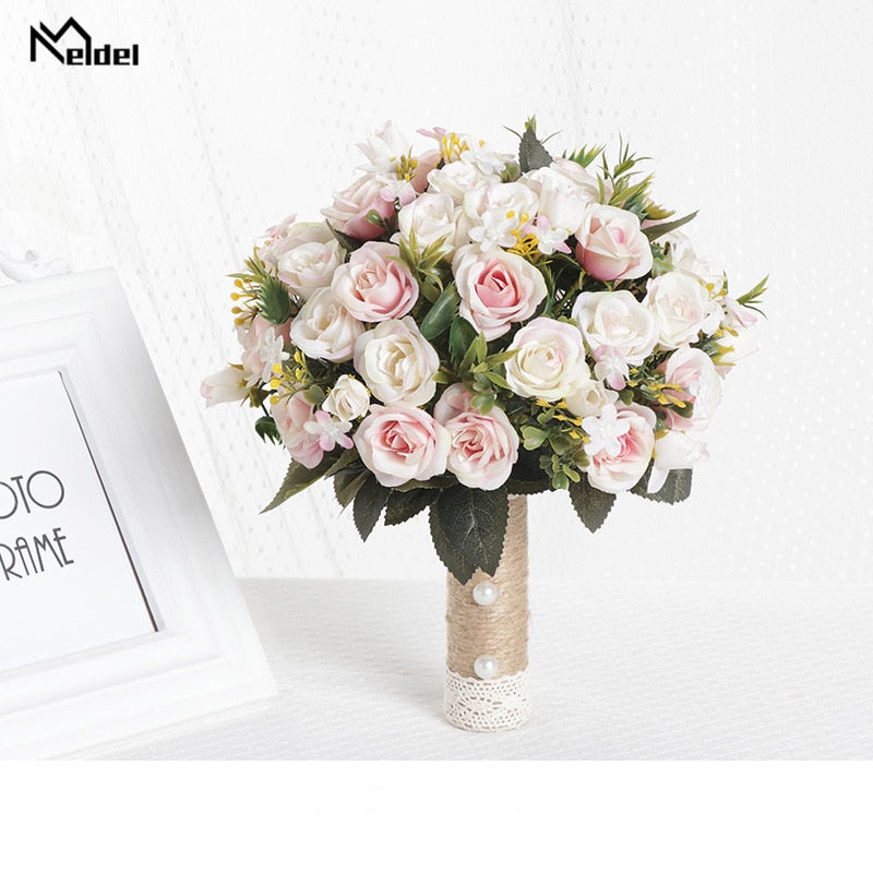 Product view of an artificial bridesmaid bouquet showcasing densely packed soft pink and blush silk roses, complete with a natural twine-wrapped handle decorated with white pearls.