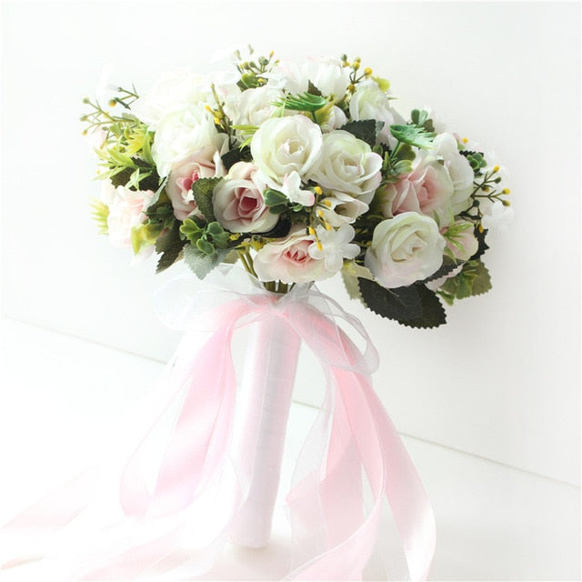 Front view of a round artificial bridal bouquet displaying mixed white and blush pink silk roses, built with a white satin stem handle and a matching trailing sheer pink bow.
