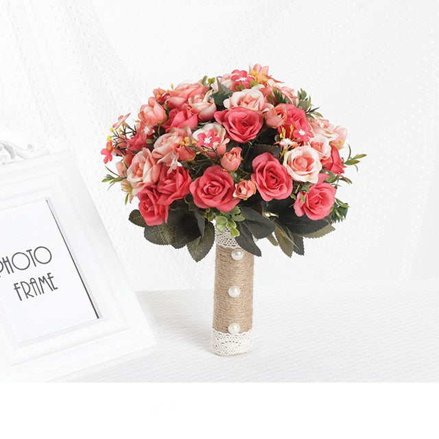 Product view of an artificial bridesmaid bouquet showcasing densely packed hot pink and coral silk roses, complete with a natural twine-wrapped handle decorated with white pearl buttons.