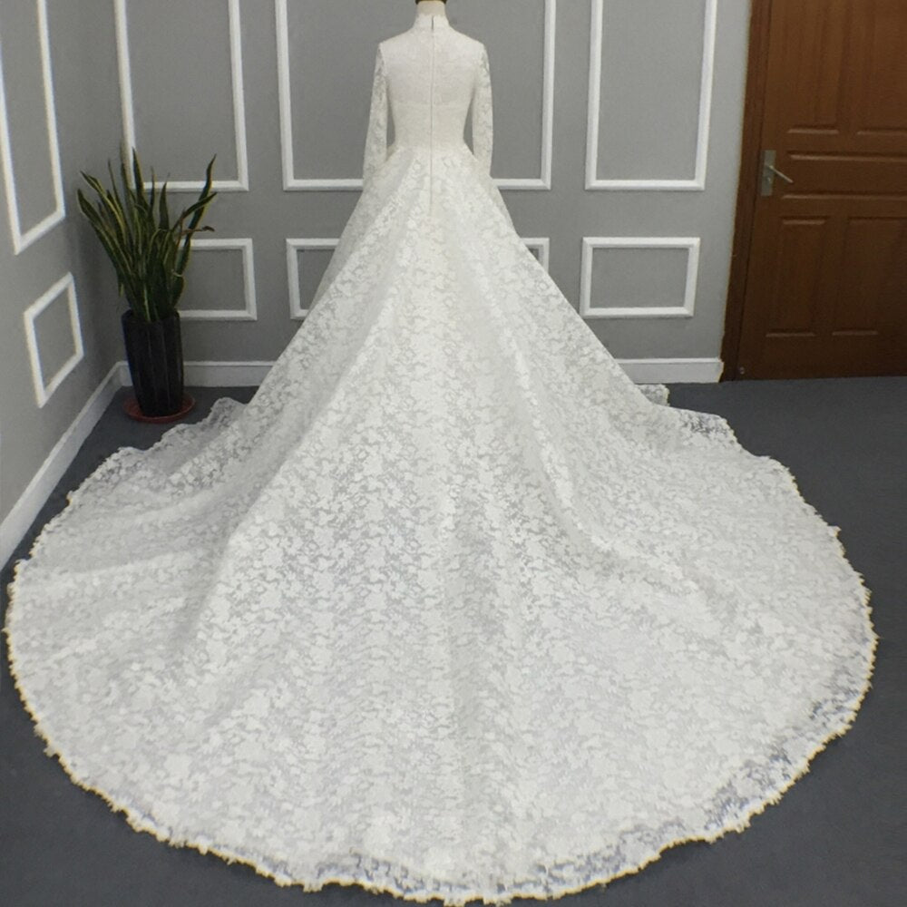 Rear view of the extensive lace train and A-line silhouette of a high neck long sleeve bridal wedding gown.