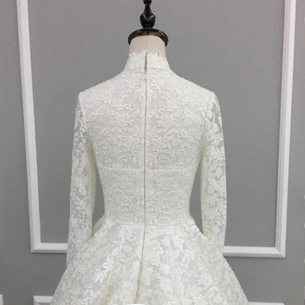 Rear view of the extensive lace train and A-line silhouette of a high neck long sleeve bridal wedding gown.