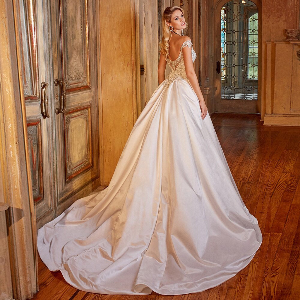 A close-up side profile of a bride in a luxury satin wedding dress, highlighting the detailed bodice and off-shoulder sleeves.