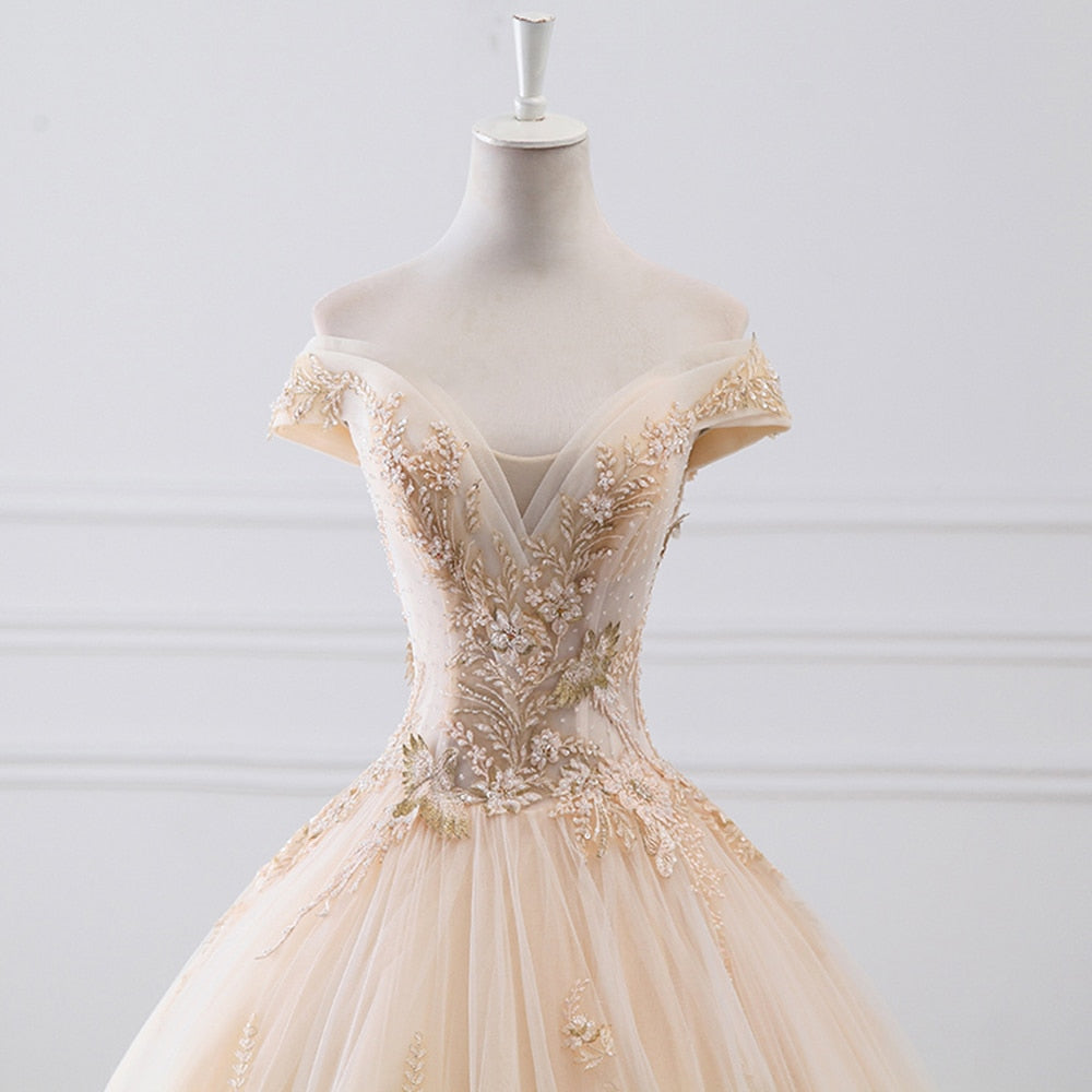 Close-up view of the off-the-shoulder neckline and delicate sparkly beadwork on a luxury ivory bridal gown.