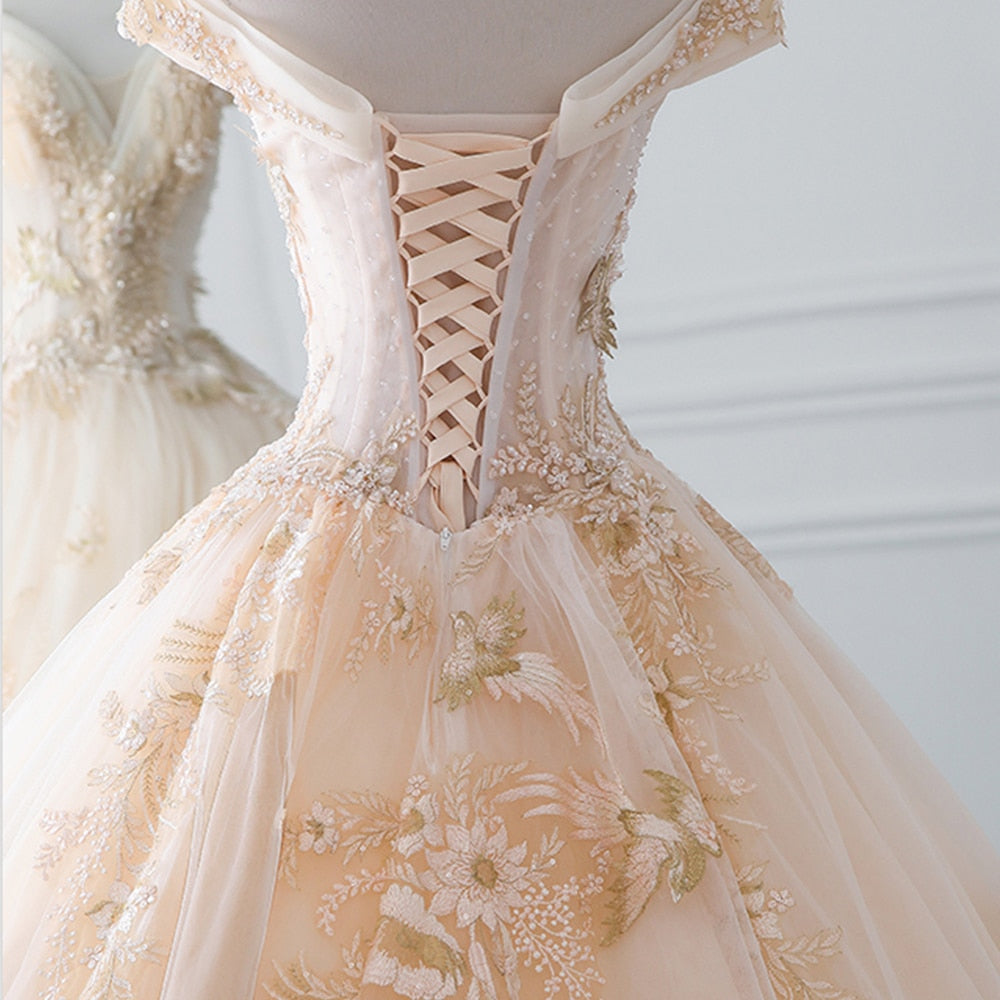 Back view of a luxury wedding dress showcasing a corset-style lace-up closure and an extensive train covered in sparkly beading and pearls.