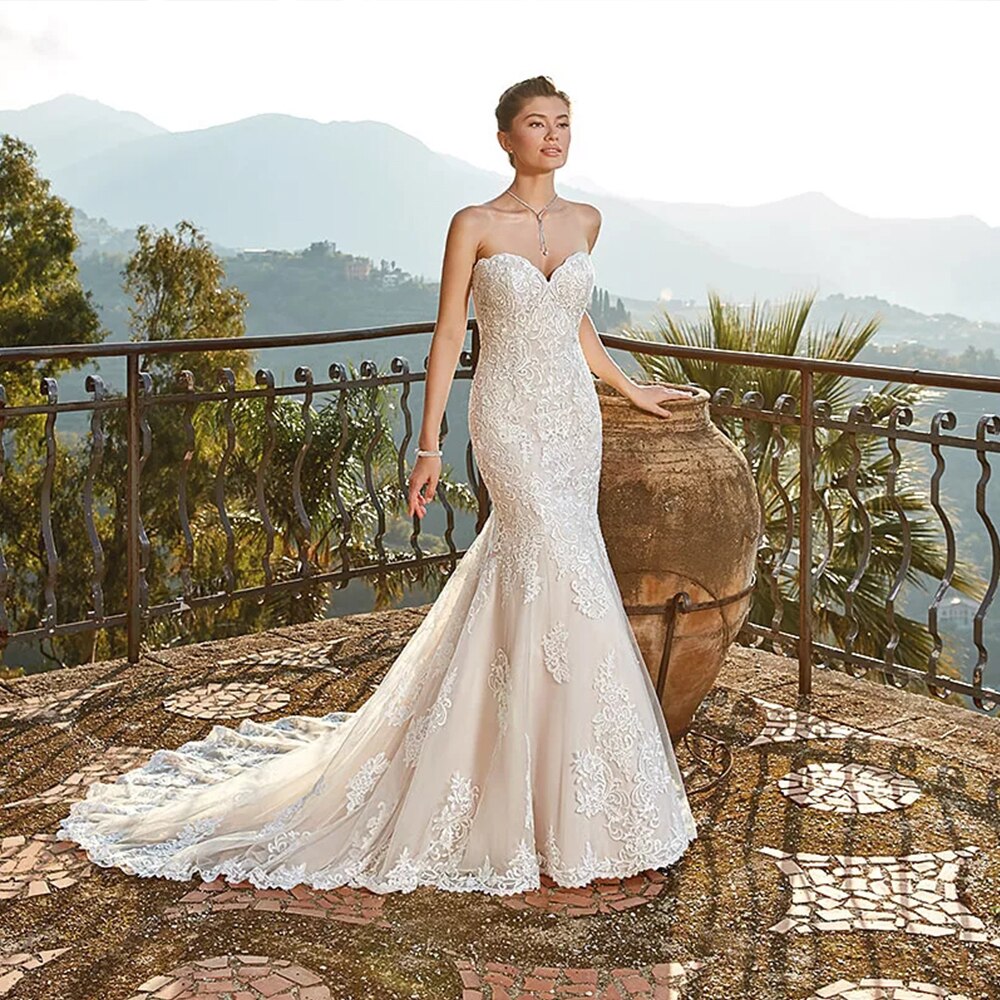 Elegant strapless mermaid wedding dress with a sweetheart neckline and intricate lace details, showcased on a terrace.