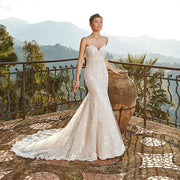 Elegant strapless mermaid wedding dress with a sweetheart neckline and intricate lace details, showcased on a terrace.